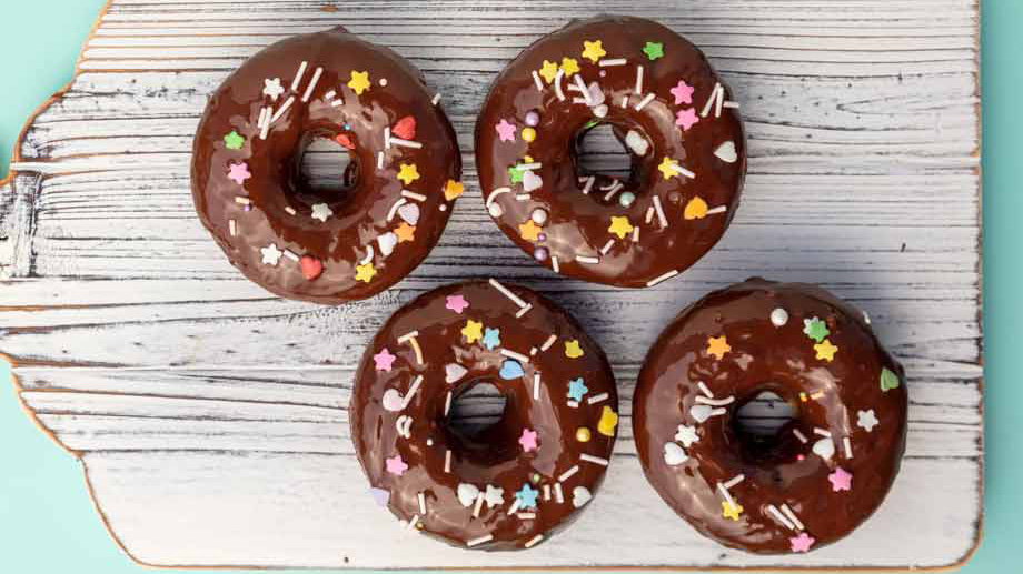 vegan banana bread donuts with chocolate glaze and pastel sprinkles.