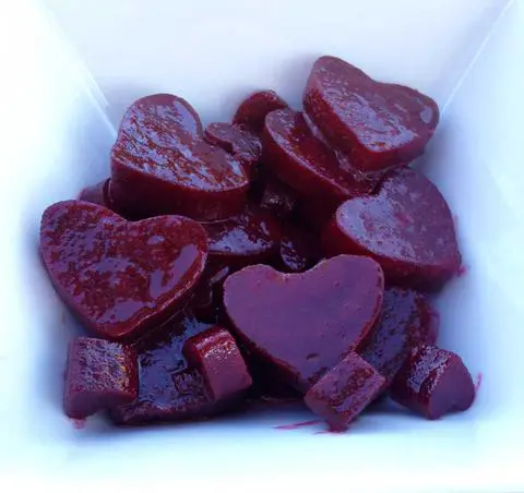 heart shaped beet salad with dressing in a white bowl.