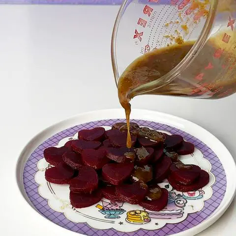 pouring dressing on a plate of heart shaped beets.