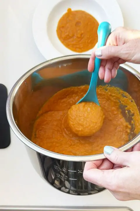 ladling vegan carrot soup into a bowl.