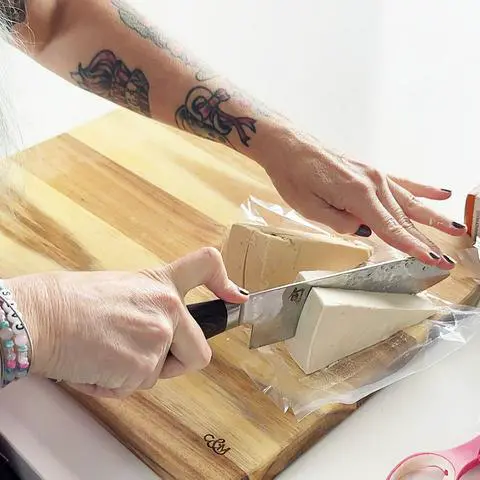 cutting 2 vegan cheese wedges into 4.