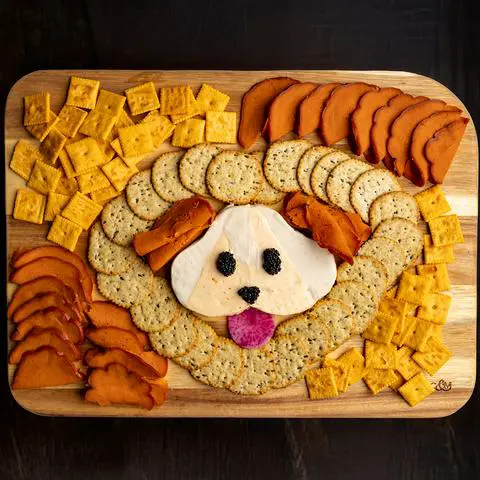 a vegan charcuterie board with vegan cheese in the center that looks like a dog.