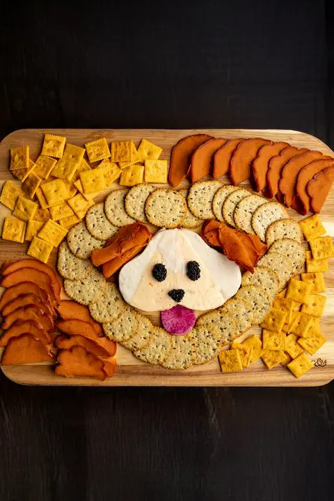 vegan cheese and cracker board with a cute cheese dog in the middle.