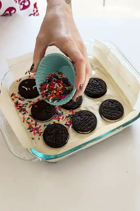 topping the oreo cheesecake brownies with vegan rainbow sprinkles.