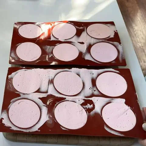 semisphere molds filled with pastel pink vegan buttercream frosting.