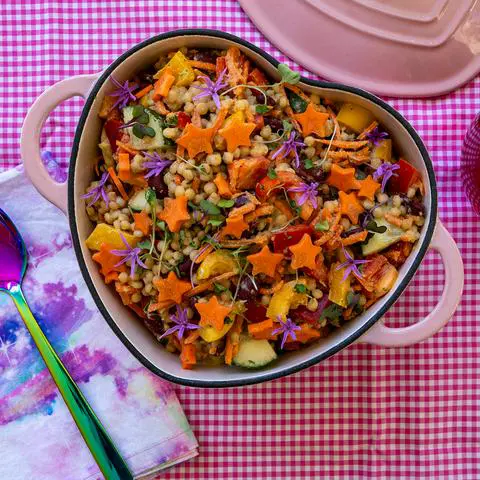 a pink heart shaped ceramic pot filled with couscous salad.
