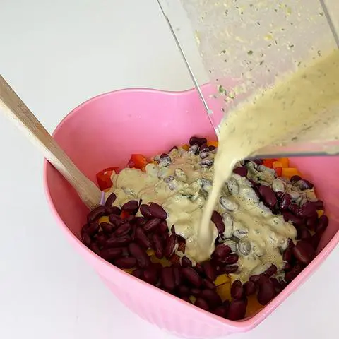 pouring salad dressing on the couscous salad.