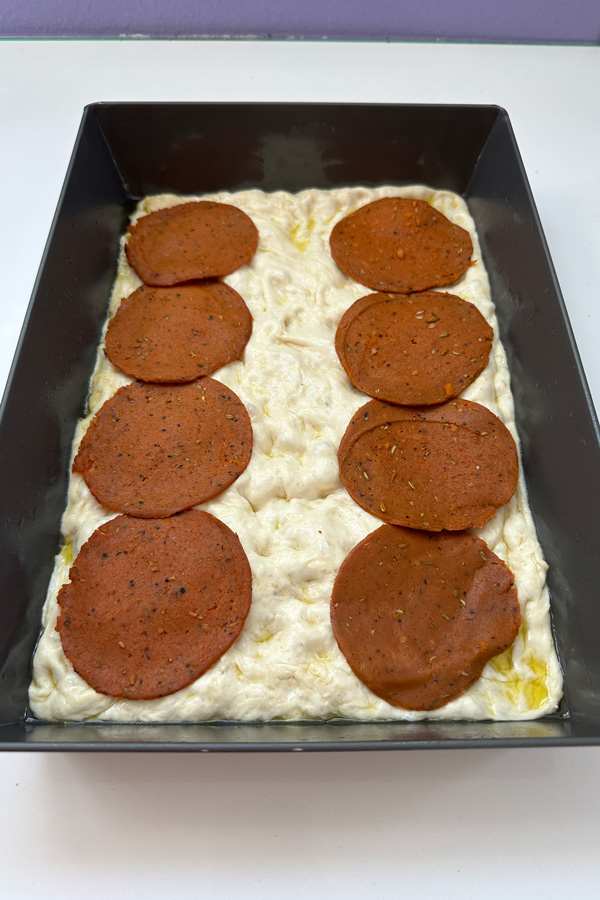 covering the pizza in vegan pepperoni