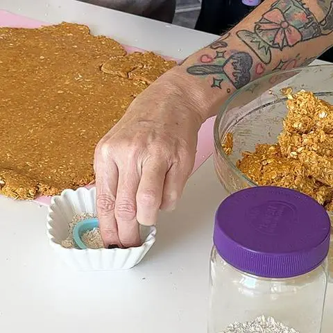 dipping the cookie cutter in oat flour.
