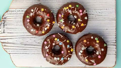 vegan banana bread donuts with chocolate glaze and pastel sprinkles.