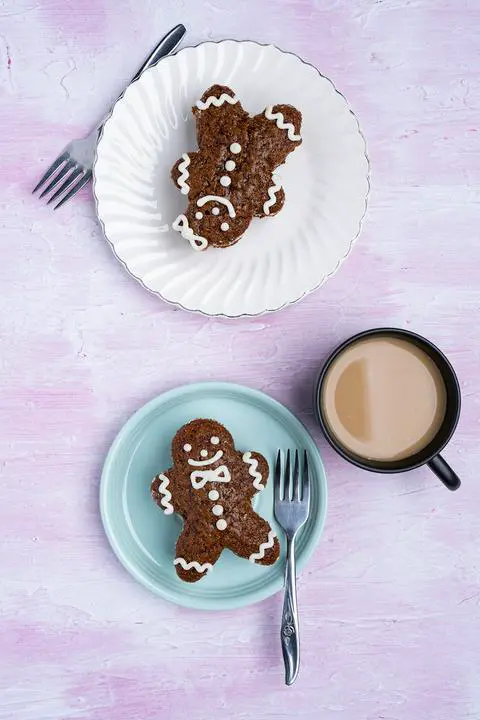 top down shot of a table with 2 plates of vegan gingerbread cake and a cup of coffee.