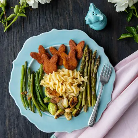 bunny-shaped vegan ham on a plate with veggies and mac n cheese.