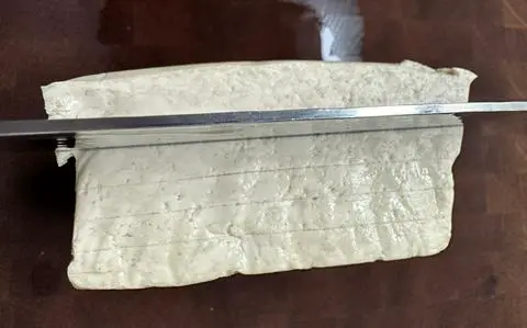 scoring the tofu to make sure the slices are an even thickness