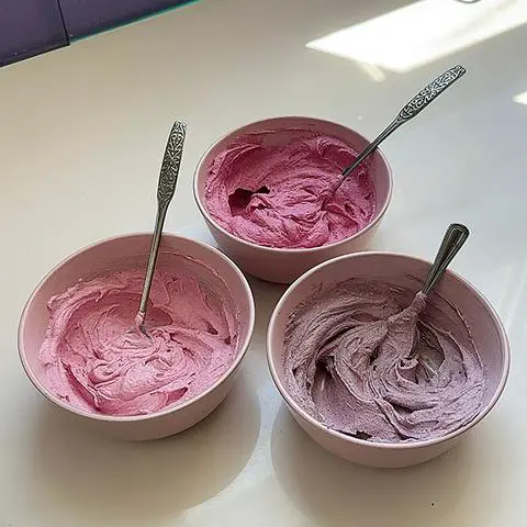 3 pink bowls filled with 3 shades of frosting.