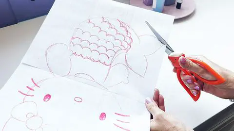 cutting out the hello kitty mermaid template out of paper.