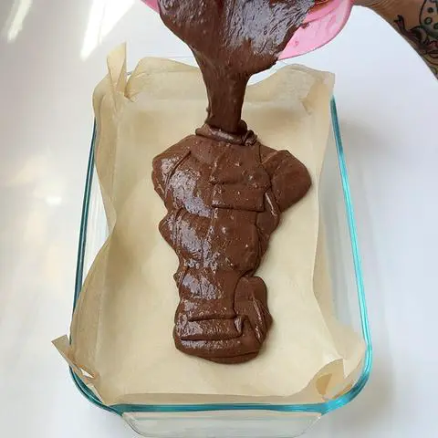 pouring chocolate cake batter into prepared pan.