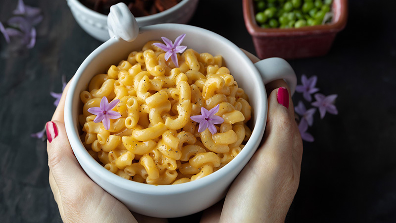 holding a bowl of vegan mac and cheese.