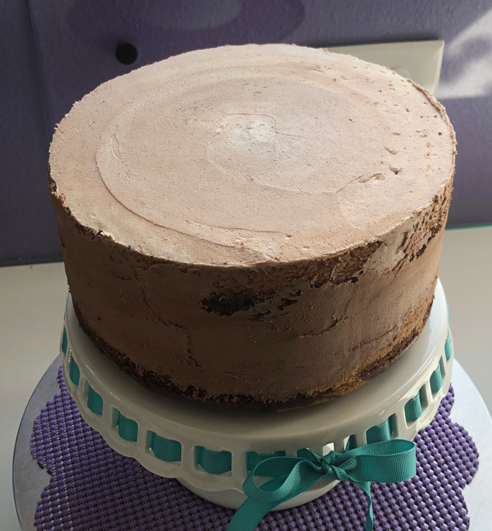 vegan marble cake covered in a crumb coat of vegan chocolate frosting