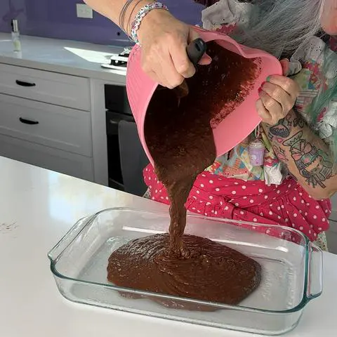pouring the vegan chocolate cake batter into the prepared pan.