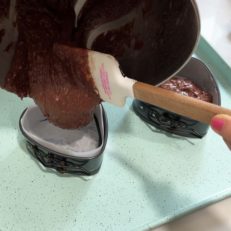 Filling cake pans with chocolate cake batter.