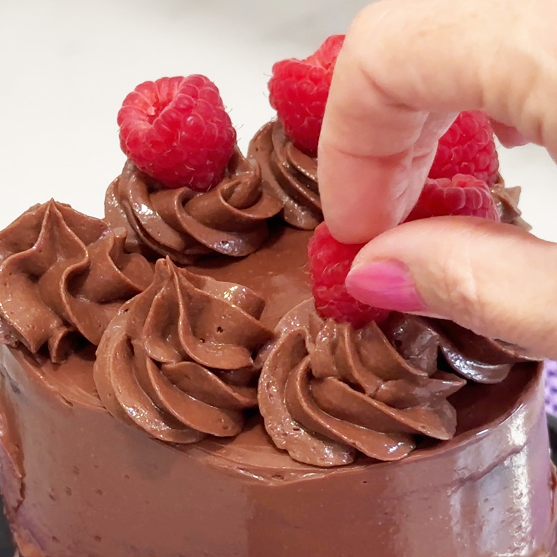 Adding raspberries to the top of the vegan gluten-free raspberry nutella cake.