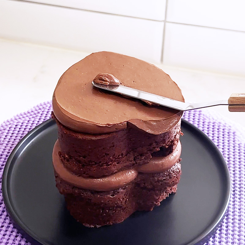 Using an offset spatula to smooth out the vegan nutella mousse on the top of the mini gluten-free raspberry nutella cake.