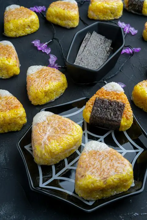 vegan tuna onigiri with a side of nori in a coffin dish and one onigiri with a piece of nori on it.