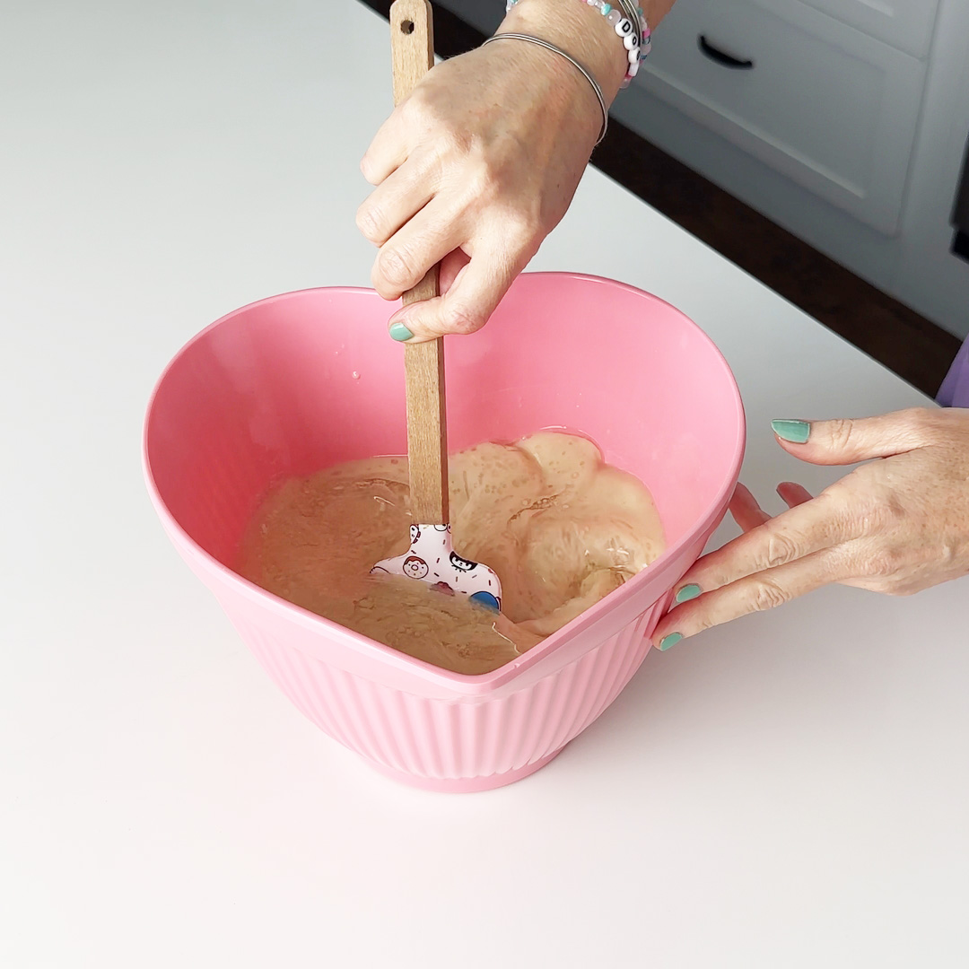mixing wet ingredients in a pink heart bowl with a hello kitty spatula.