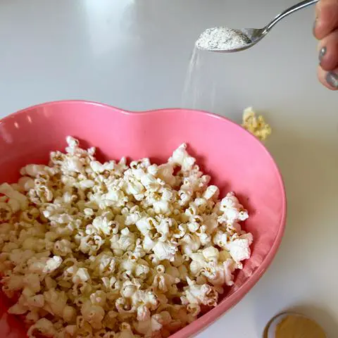sprinkling popcorn with dill pickle seasoning