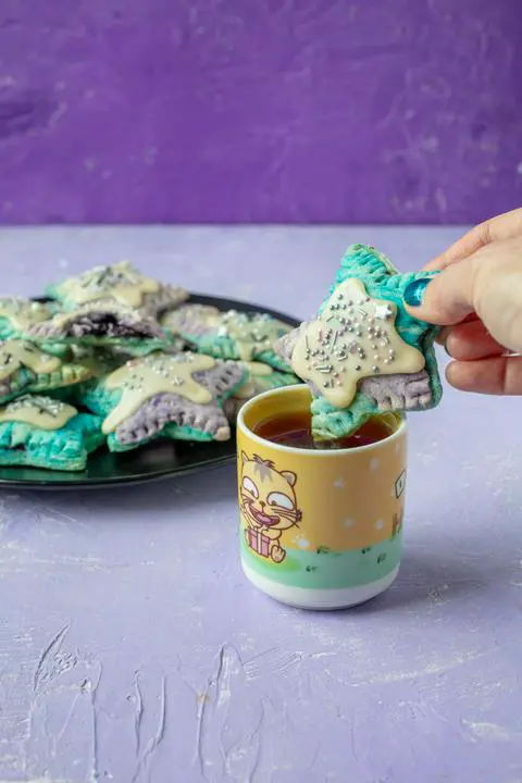 dipping a mini vegan blueberry pop tart into tea.