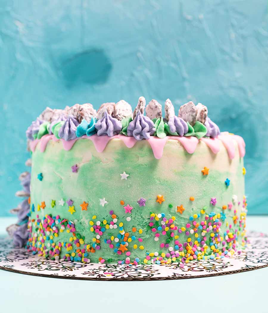 vegan chocolate cake, filled with puppy chow and peanut butter frosting, topped with puppy chow and sprinkles