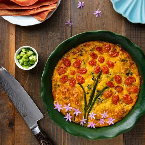 Vegan gluten-free quiche made with Just Egg and decorated with tomatoes and asparagus.