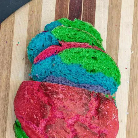 vegan rainbow bread sliced on a cutting board.