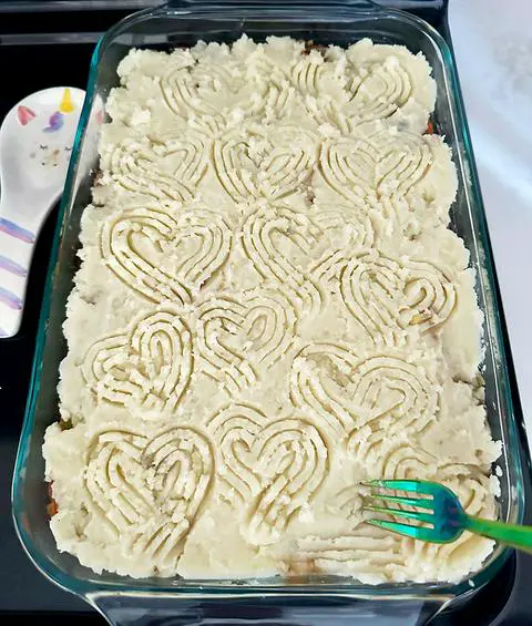 a 9x13 pan of shepherd's pie scored with hearts using a fork.