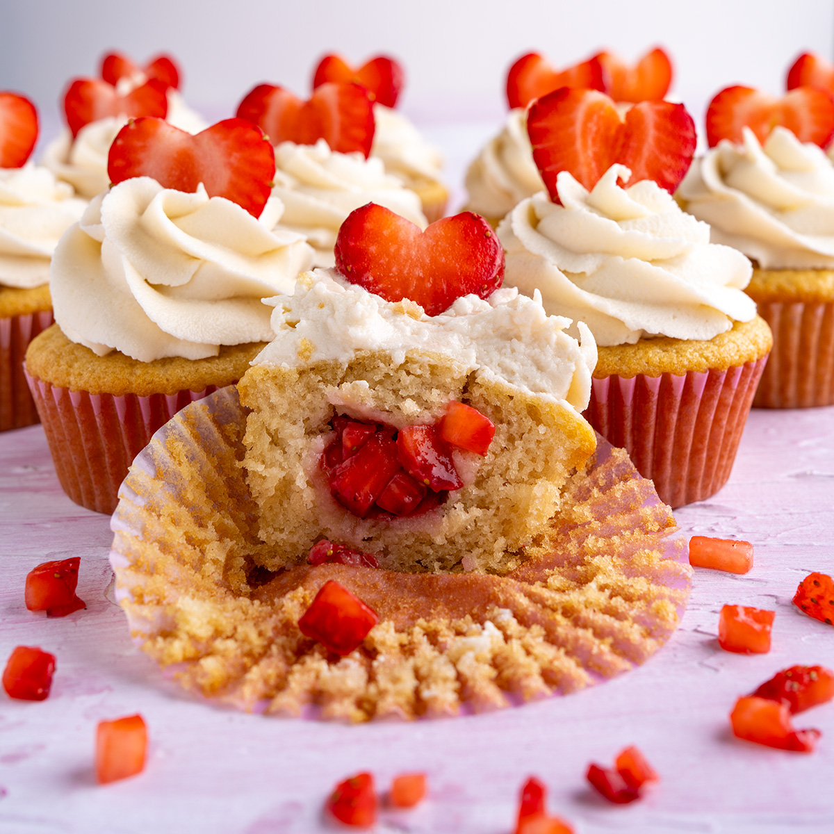 a vegan cupcake with strawberry filling and a strawberry heart on top.