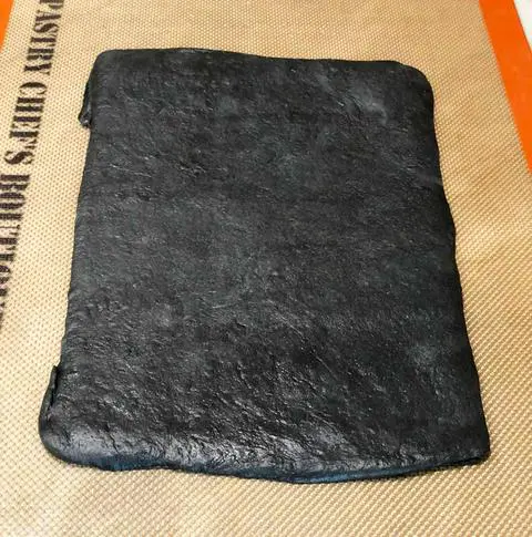 black bread dough rolled out into a rectangle shape