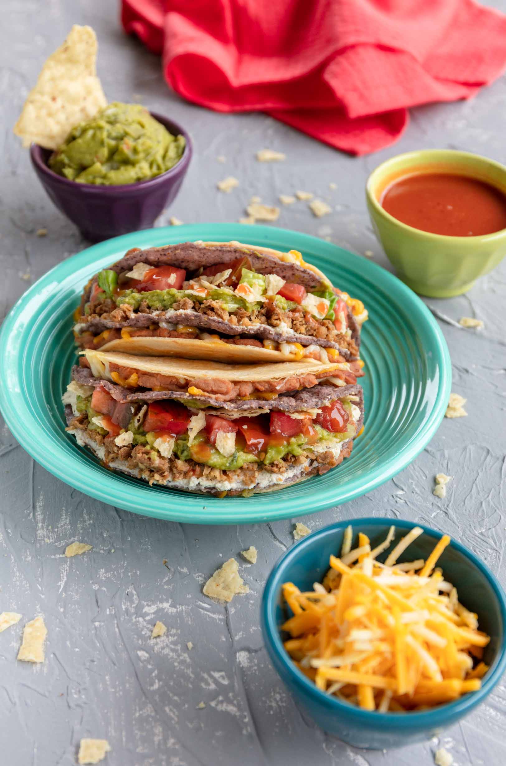 vegan loaded tacos inside a grilled taco on a plate with chips and guacamole in the background