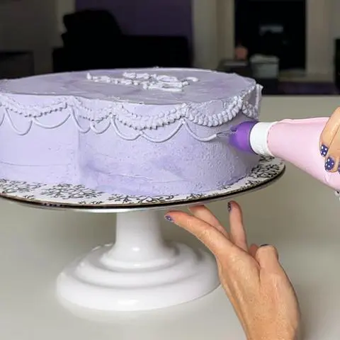 piping drop strings onto the sides of the heart cake.