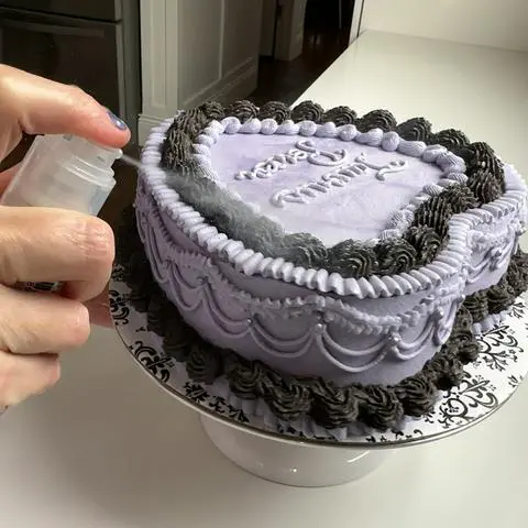 spraying glitter onto the cake.