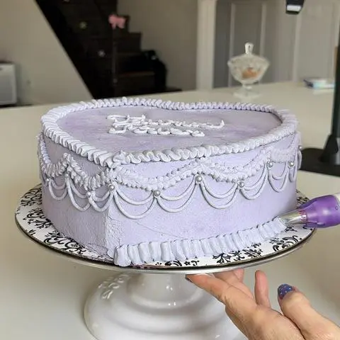 piping the ruffle border at the bottom of the cake.