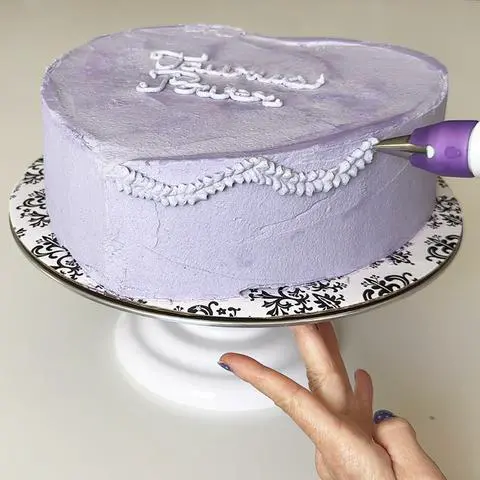 piping looping ruffles onto the side of the cake.