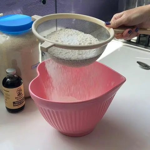 sifting dry ingredients into a pink heart bowl.