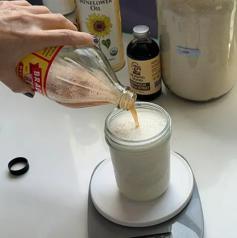 adding apple cider vinegar to a jar of vegan milk.