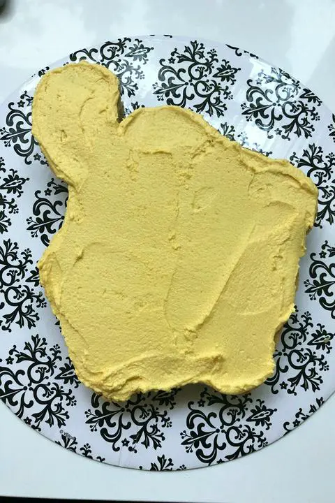 the bottom layer of cake covered in yellow vanilla frosting