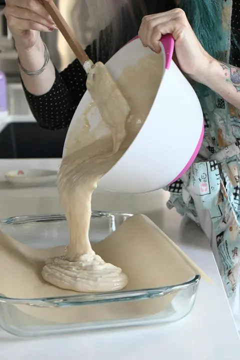 pouring the vegan cake batter into the baking pan.
